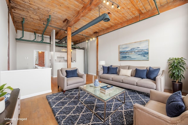 living area featuring beam ceiling, wood finished floors, wood ceiling, and baseboards