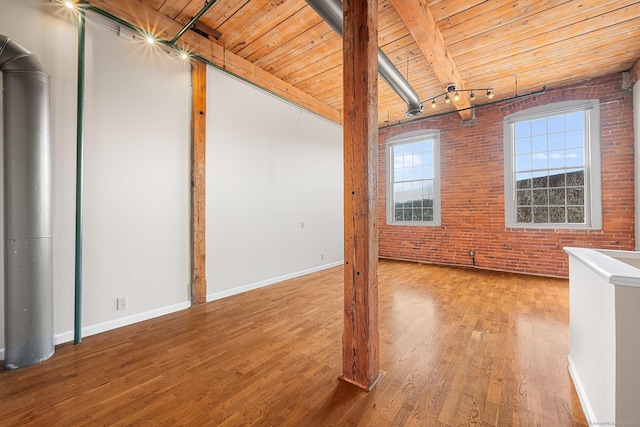 interior space with brick wall, wood finished floors, wood ceiling, baseboards, and beamed ceiling