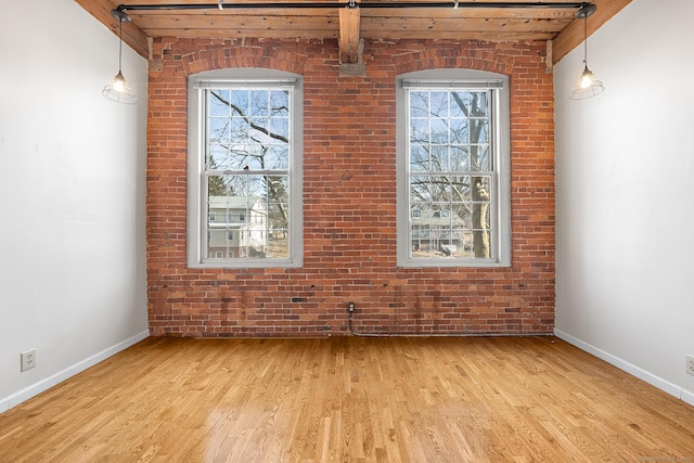 interior space featuring brick wall, light wood-style flooring, and baseboards