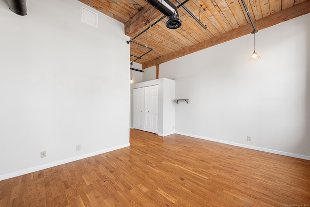 spare room featuring wooden ceiling, wood finished floors, visible vents, baseboards, and beam ceiling