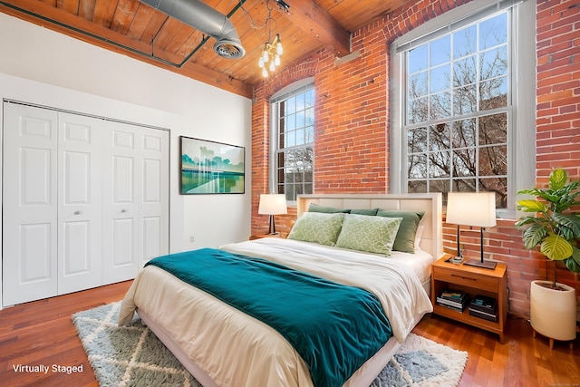 bedroom featuring brick wall, wood finished floors, and wood ceiling