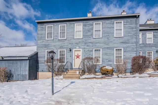 colonial-style house featuring entry steps and a chimney