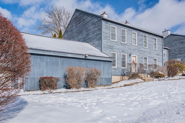 view of snow covered exterior with a chimney