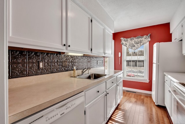 kitchen featuring light countertops, white appliances, white cabinets, and a sink