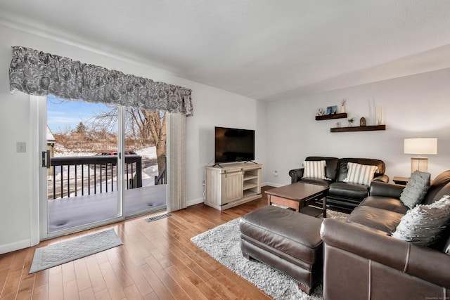 living area featuring light wood-style flooring, visible vents, and baseboards