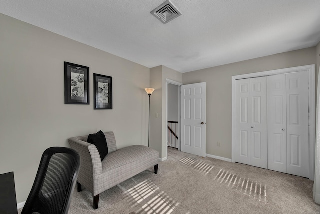 sitting room with a textured ceiling, carpet flooring, an upstairs landing, visible vents, and baseboards