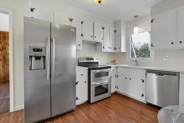 kitchen with stainless steel appliances, light countertops, hanging light fixtures, white cabinetry, and a sink