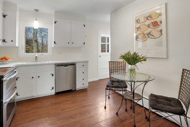 kitchen featuring white cabinets, decorative light fixtures, light countertops, stainless steel appliances, and a sink