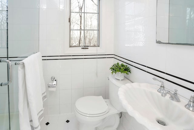 bathroom with a sink, tile walls, and toilet