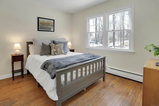 bedroom with baseboards, a baseboard heating unit, and hardwood / wood-style floors