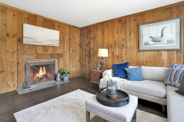 living area with dark wood-style floors, wooden walls, and a fireplace