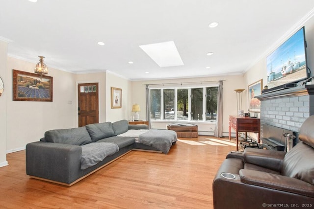 living room with a skylight, light wood finished floors, recessed lighting, ornamental molding, and a brick fireplace