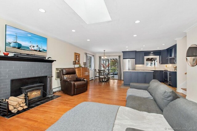 living area featuring ornamental molding, recessed lighting, light wood-style flooring, and a skylight