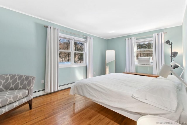 bedroom featuring baseboard heating and wood finished floors