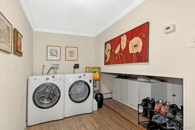 washroom with laundry area, ornamental molding, washer and dryer, light wood-type flooring, and a baseboard heating unit