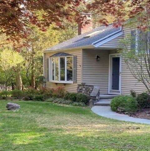 view of front of house with a chimney and a front lawn