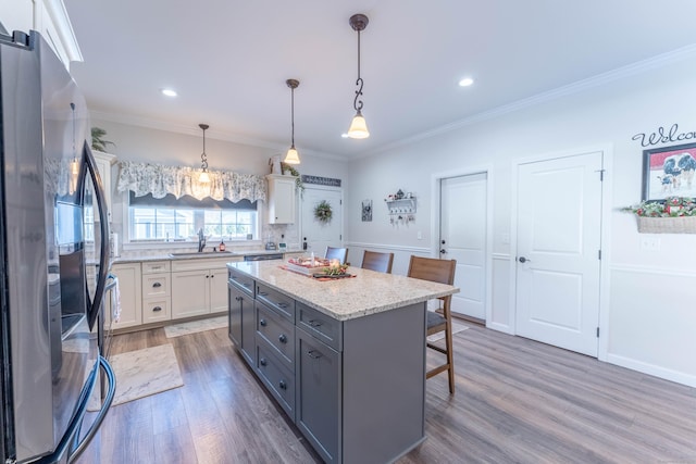 kitchen with a kitchen island, white cabinetry, gray cabinets, freestanding refrigerator, and a kitchen bar