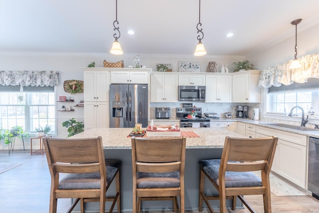 kitchen with pendant lighting, stainless steel appliances, a sink, and a center island