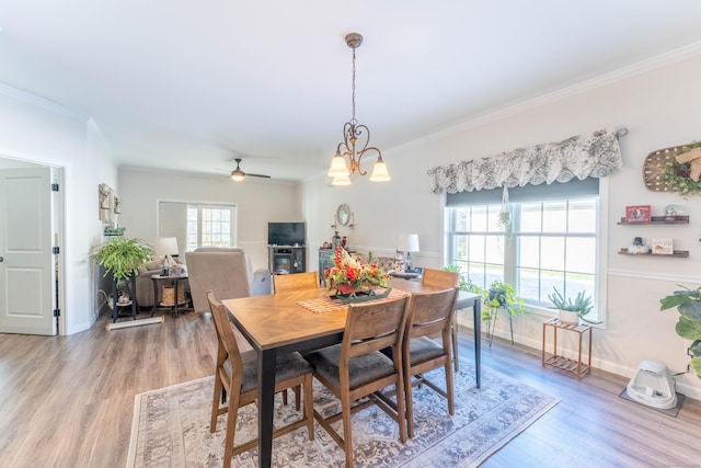 dining room with baseboards, ceiling fan with notable chandelier, wood finished floors, and crown molding