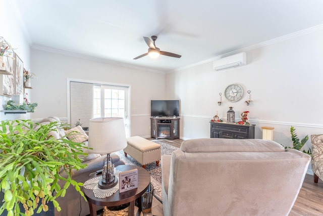 living room featuring ceiling fan, a wall unit AC, light wood-style floors, ornamental molding, and a glass covered fireplace