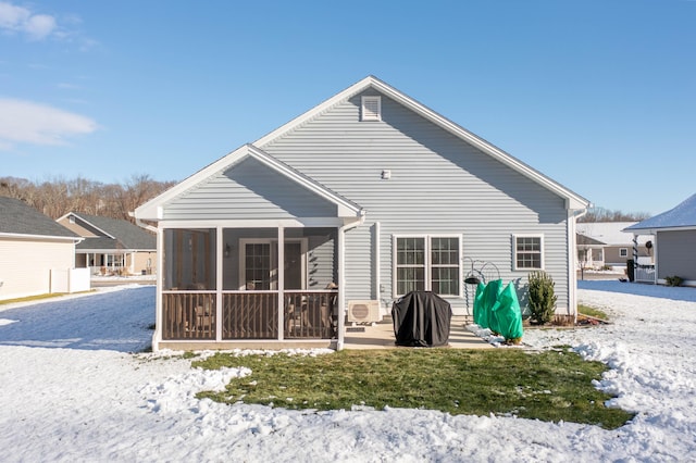 snow covered rear of property with a sunroom