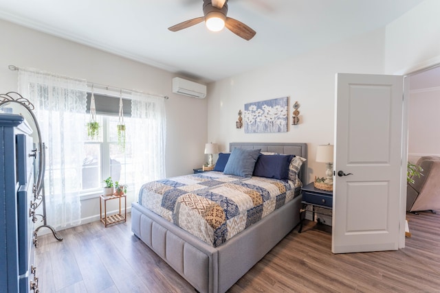 bedroom with ceiling fan, an AC wall unit, and wood finished floors