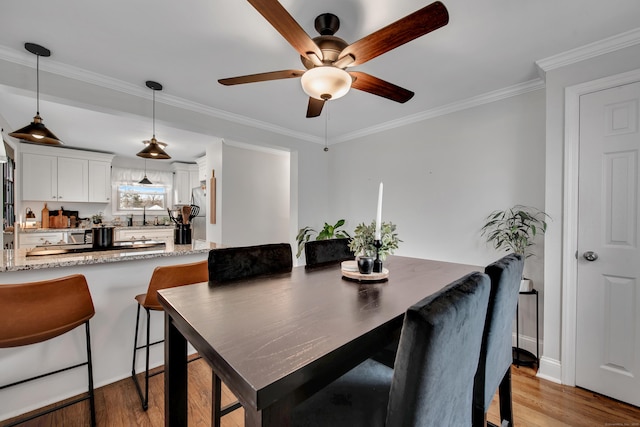 dining room featuring light wood-type flooring, ceiling fan, and crown molding