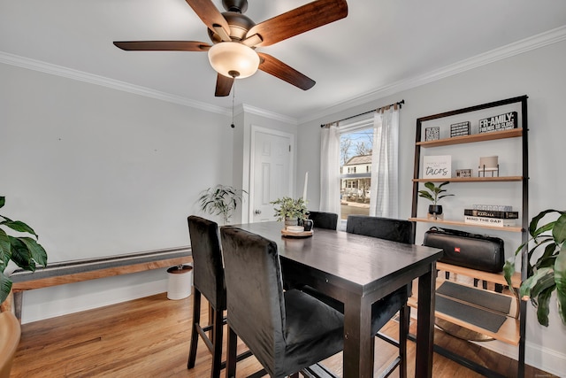 dining area with baseboards, light wood-style floors, and crown molding