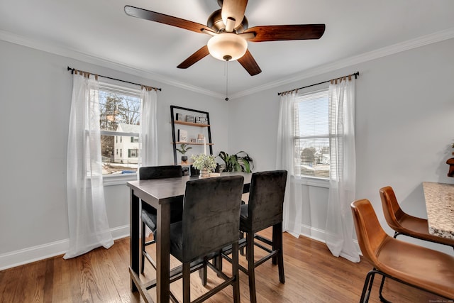 dining space with ornamental molding, baseboards, ceiling fan, and light wood finished floors