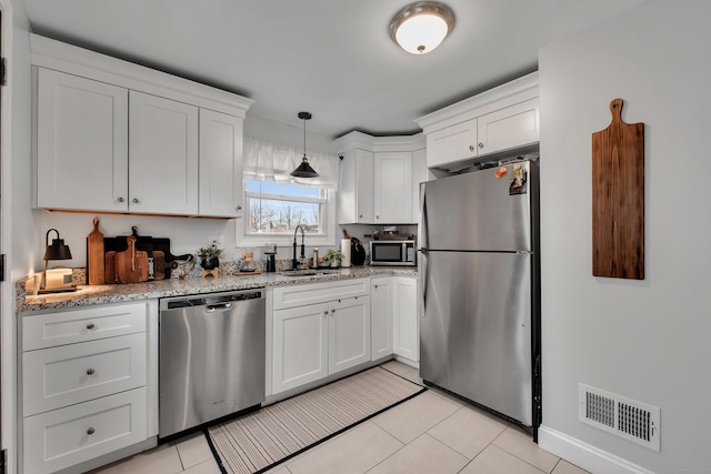 kitchen with visible vents, white cabinets, appliances with stainless steel finishes, a sink, and light tile patterned flooring