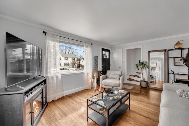 living area featuring light wood finished floors, baseboards, stairs, and ornamental molding