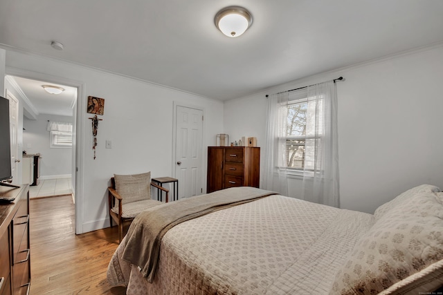 bedroom featuring light wood-style flooring, baseboards, and crown molding