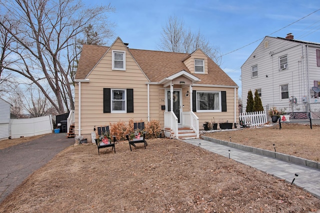 view of front of home featuring a shingled roof, fence, and driveway