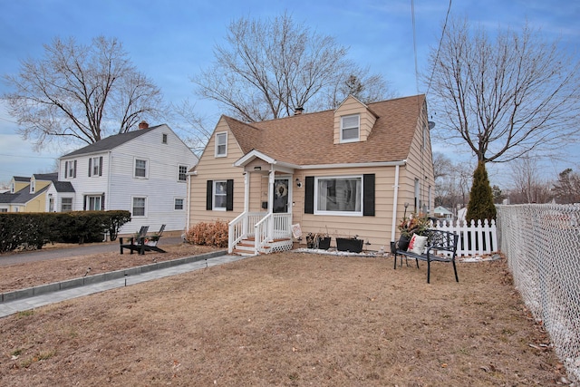 view of front of property with a shingled roof and fence