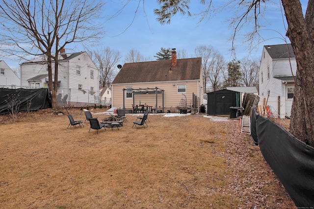 rear view of property featuring an outbuilding, an outdoor fire pit, cooling unit, fence, and a storage unit