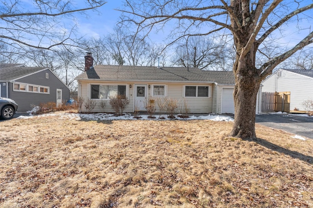 ranch-style home featuring a garage, fence, a chimney, and aphalt driveway