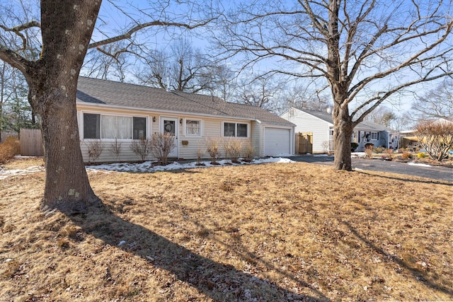 single story home with driveway, roof with shingles, an attached garage, and fence