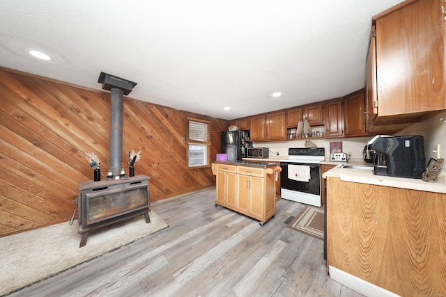 kitchen with wooden walls, range with electric cooktop, light countertops, light wood-type flooring, and brown cabinetry