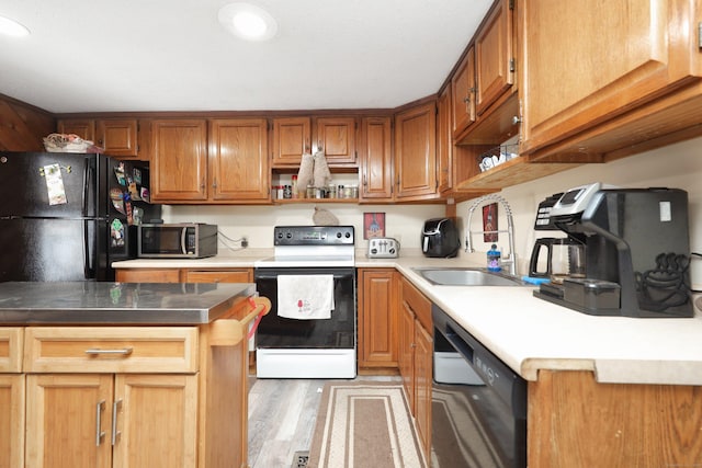 kitchen featuring light wood finished floors, open shelves, brown cabinetry, a sink, and black appliances