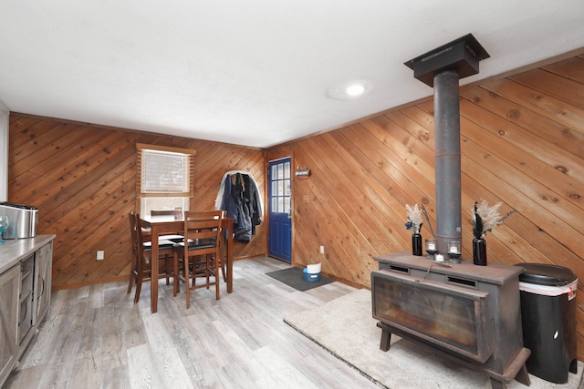 dining area with light wood-style floors, a wood stove, and baseboards