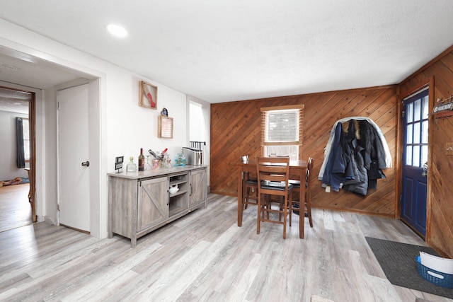 dining space featuring light wood-type flooring and wooden walls