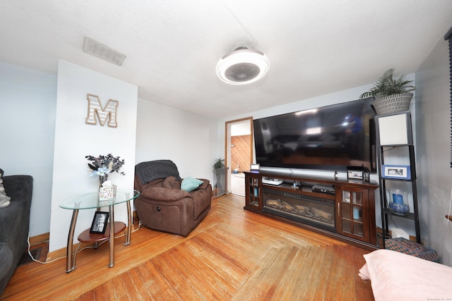 living area with baseboards, visible vents, and wood finished floors