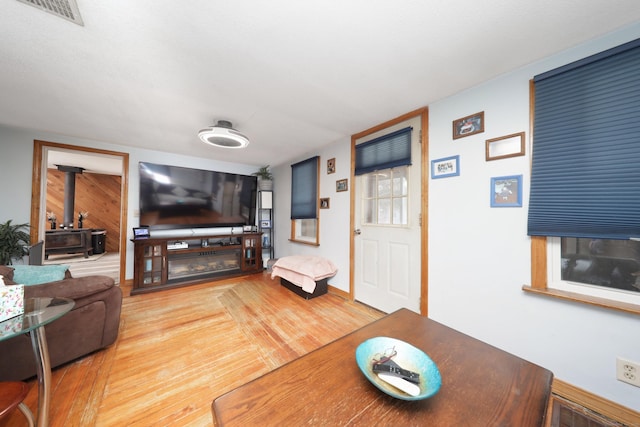 living area with a wood stove, visible vents, and wood finished floors