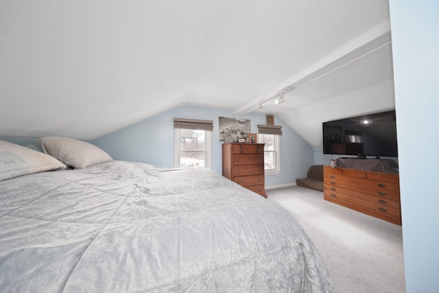 bedroom featuring light carpet, track lighting, vaulted ceiling, and baseboards