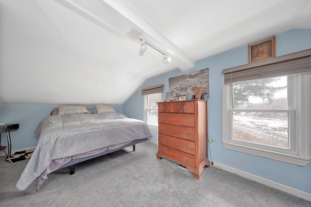 carpeted bedroom featuring lofted ceiling with beams, baseboards, and track lighting