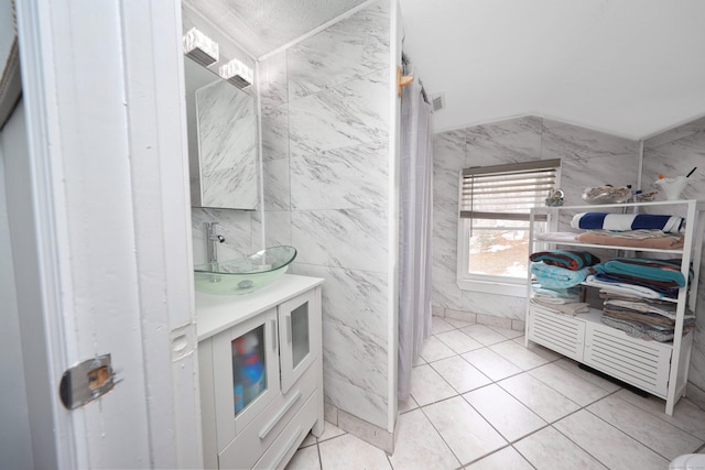 bathroom featuring tile walls, lofted ceiling, tile patterned flooring, vanity, and a closet