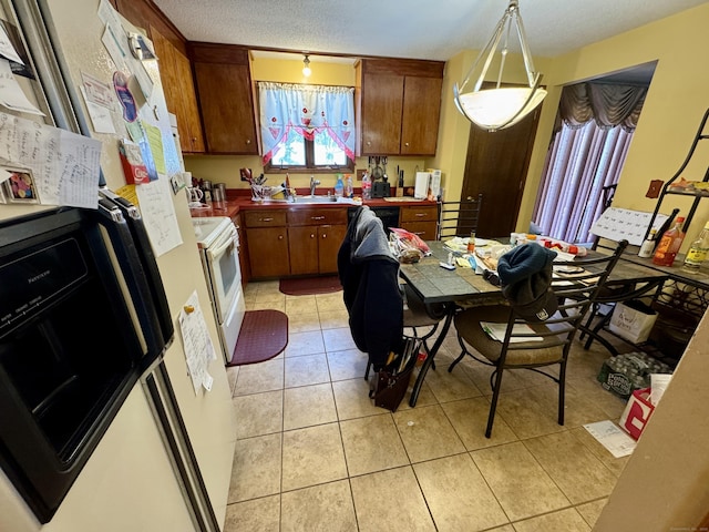 kitchen with light tile patterned floors, a textured ceiling, a sink, freestanding refrigerator, and white range with electric cooktop