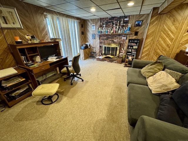 office with a brick fireplace, wooden walls, and carpet flooring