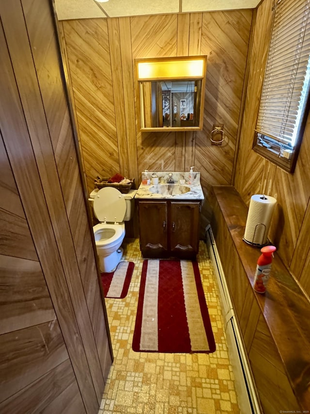 half bath featuring wood walls, vanity, and toilet