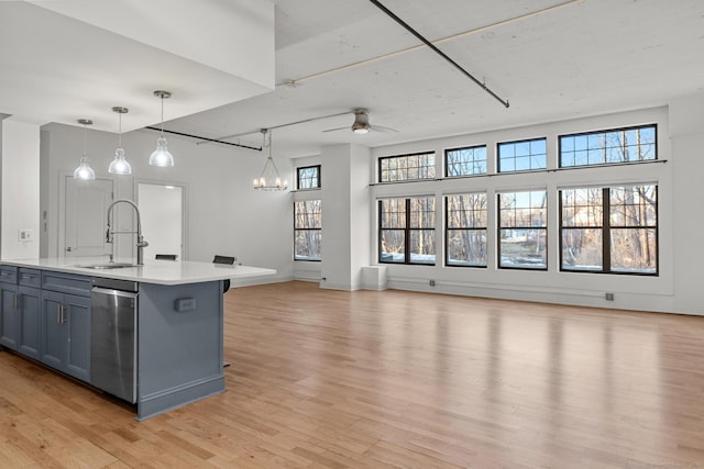 kitchen with dishwasher, open floor plan, light countertops, light wood-type flooring, and a sink